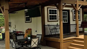 A covered patio area with a table and chairs, a wooden deck, and a metal roof.
