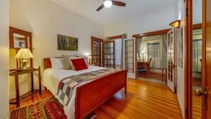 A bedroom with a wooden bed, a ceiling fan, and a view of the outside through a glass door.