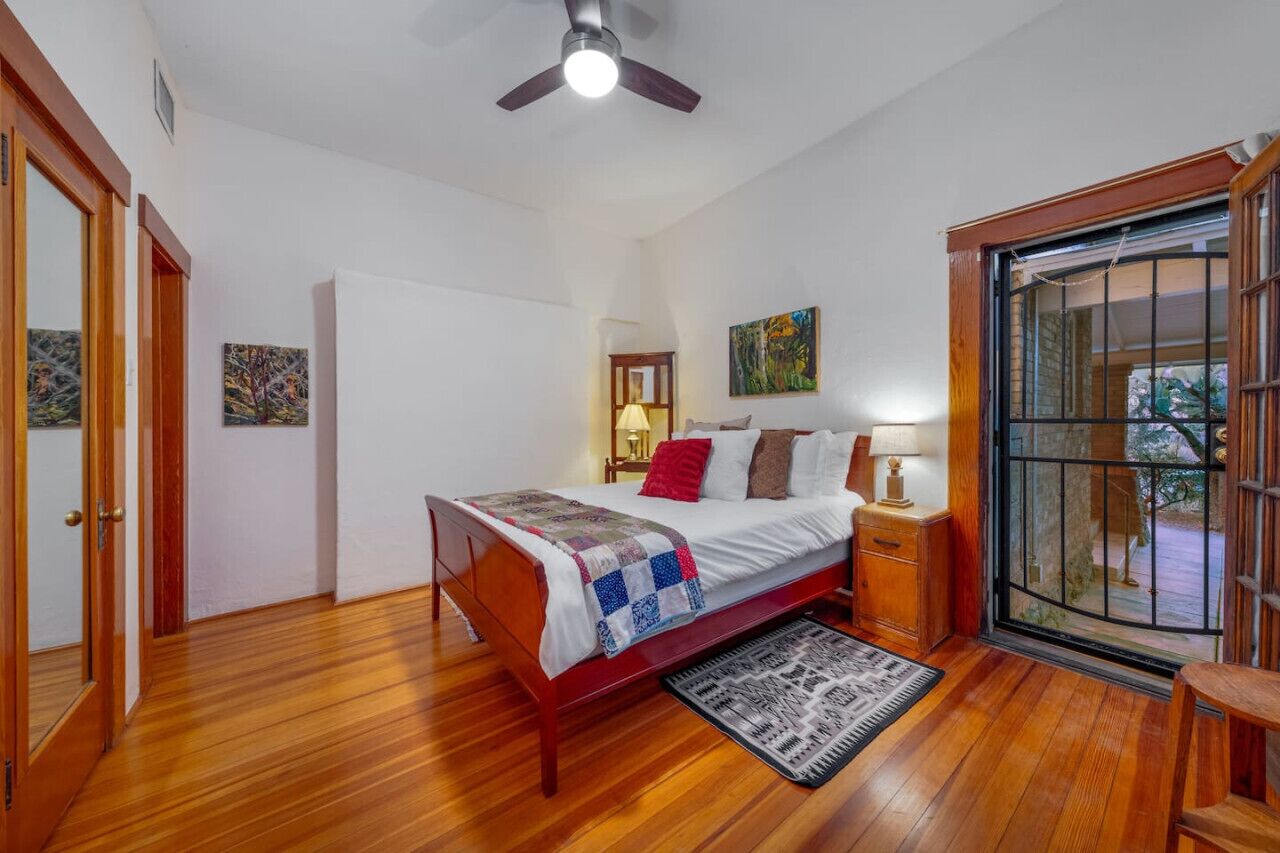 A bedroom with a wooden bed, a nightstand, a lamp, and a view through a glass door.