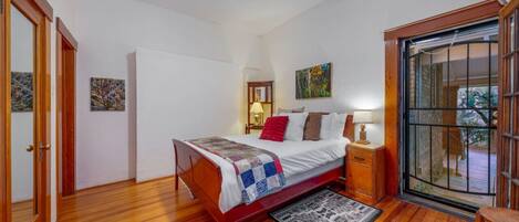 A bedroom with a wooden bed, a nightstand, a lamp, and a view through a glass door.