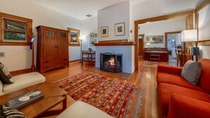 A living room with a fireplace, wooden furniture, and a red sofa.