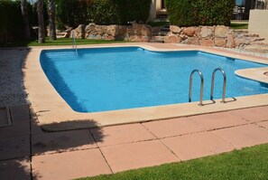 Relax by the rectangular pool surrounded by a lawn and lush greenery.