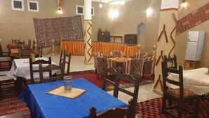 A dining area with tables set for meals, chairs, and a buffet table. - Sahara Garden (Rissani)