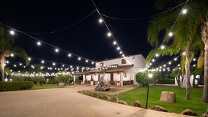 Een gebouw met een overdekt terras, buiten zitplaatsen en lichtjes.