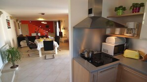 Una cucina moderna con piano cottura, forno a microonde e tostapane. C'è un'area pranzo con tavolo e sedie.
