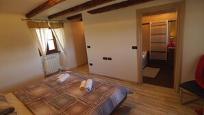 Una camera da letto con un letto, una finestra con tende, un termosifone e una porta che conduce al bagno.