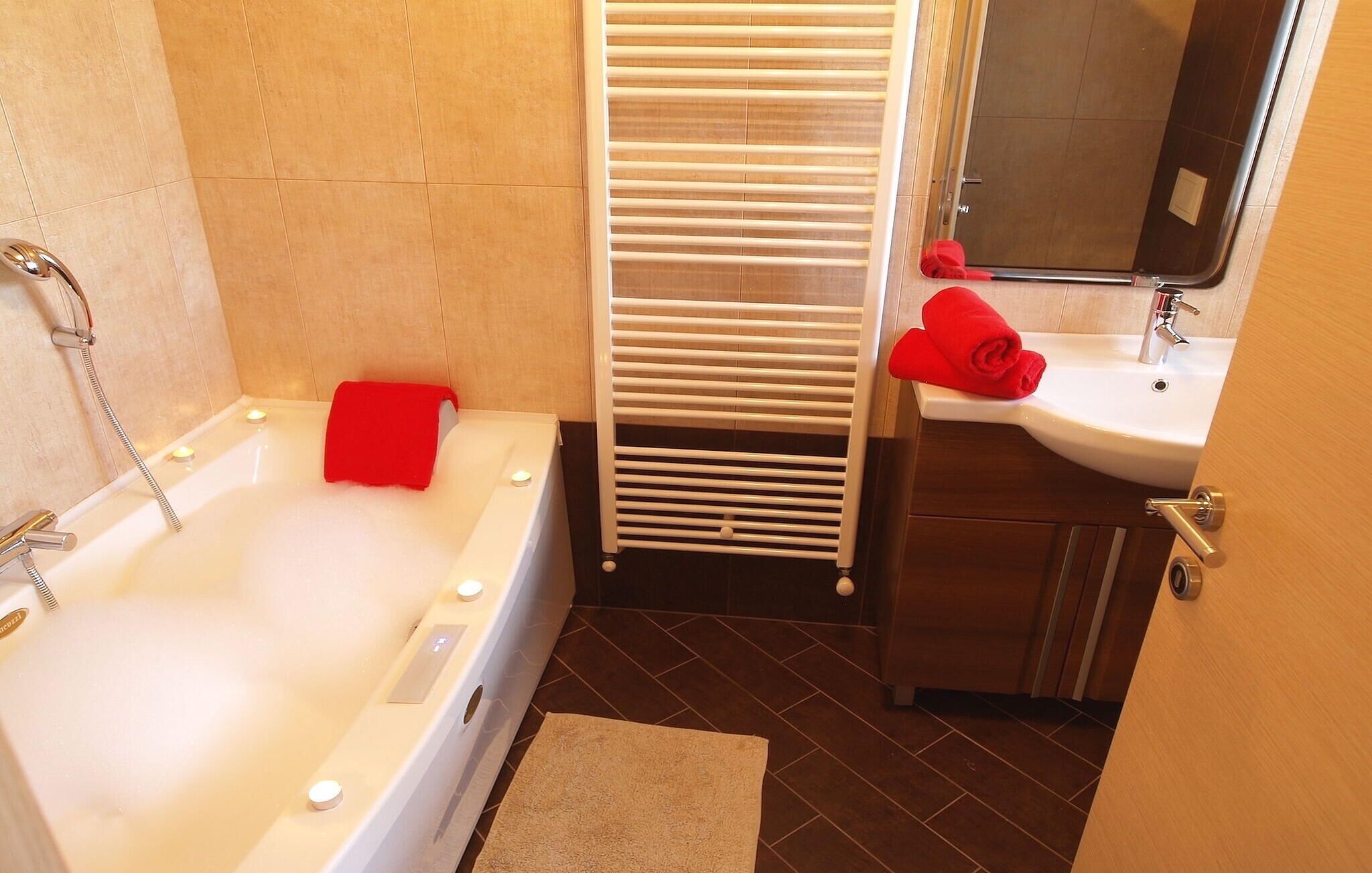 Un baño con bañera, un toallero blanco, una toalla roja, un lavabo y un espejo.