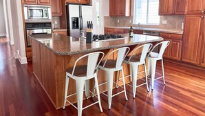 A modern kitchen with wooden cabinets, a granite countertop, and a central island with bar stools. - Spacious 5 Bedrooms, 7 beds - Sleeps Large Groups (Portland)