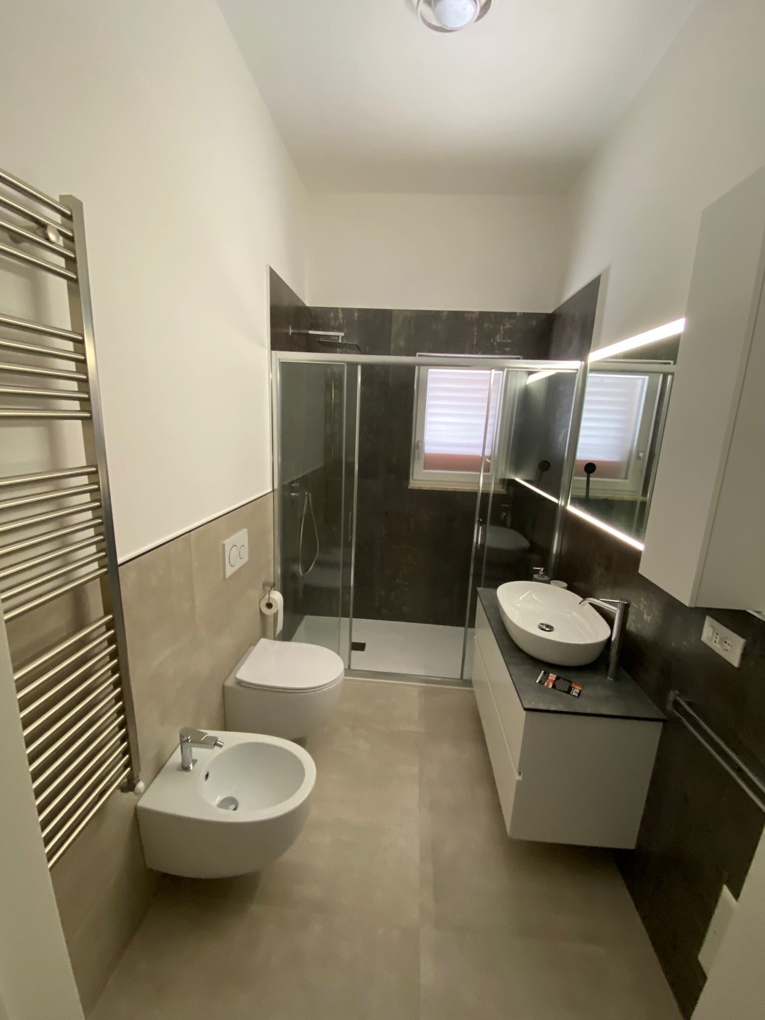 A modern bathroom with a glass-enclosed shower, a toilet, and two sinks.