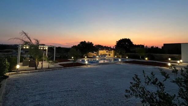 Un área de piscina en la azotea con una pérgola y asientos, rodeada por un deck de grava.