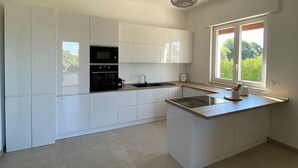 Una cocina moderna con armarios blancos, una estufa negra y una ventana que proporciona luz natural.