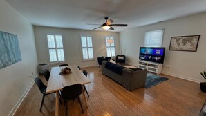 A spacious living room with a dining area, a sofa, a TV, and large windows. - Spacious 3BR 3BA above Brewery, Pizza Shop & Arcade 5 mins to DT Indy (Indianapolis)