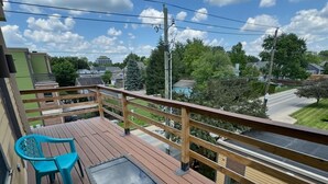 A wooden deck with a glass table and two chairs, overlooking a residential area with houses and trees. - Spacious 3BR 3BA above Brewery, Pizza Shop & Arcade 5 mins to DT Indy (Indianapolis)