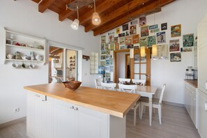 A kitchen with a wooden island, white cabinetry, and a wall adorned with vintage posters.