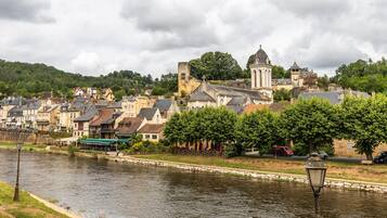 A riverside town with historic buildings, a prominent church tower, and a paved walkway along the water.