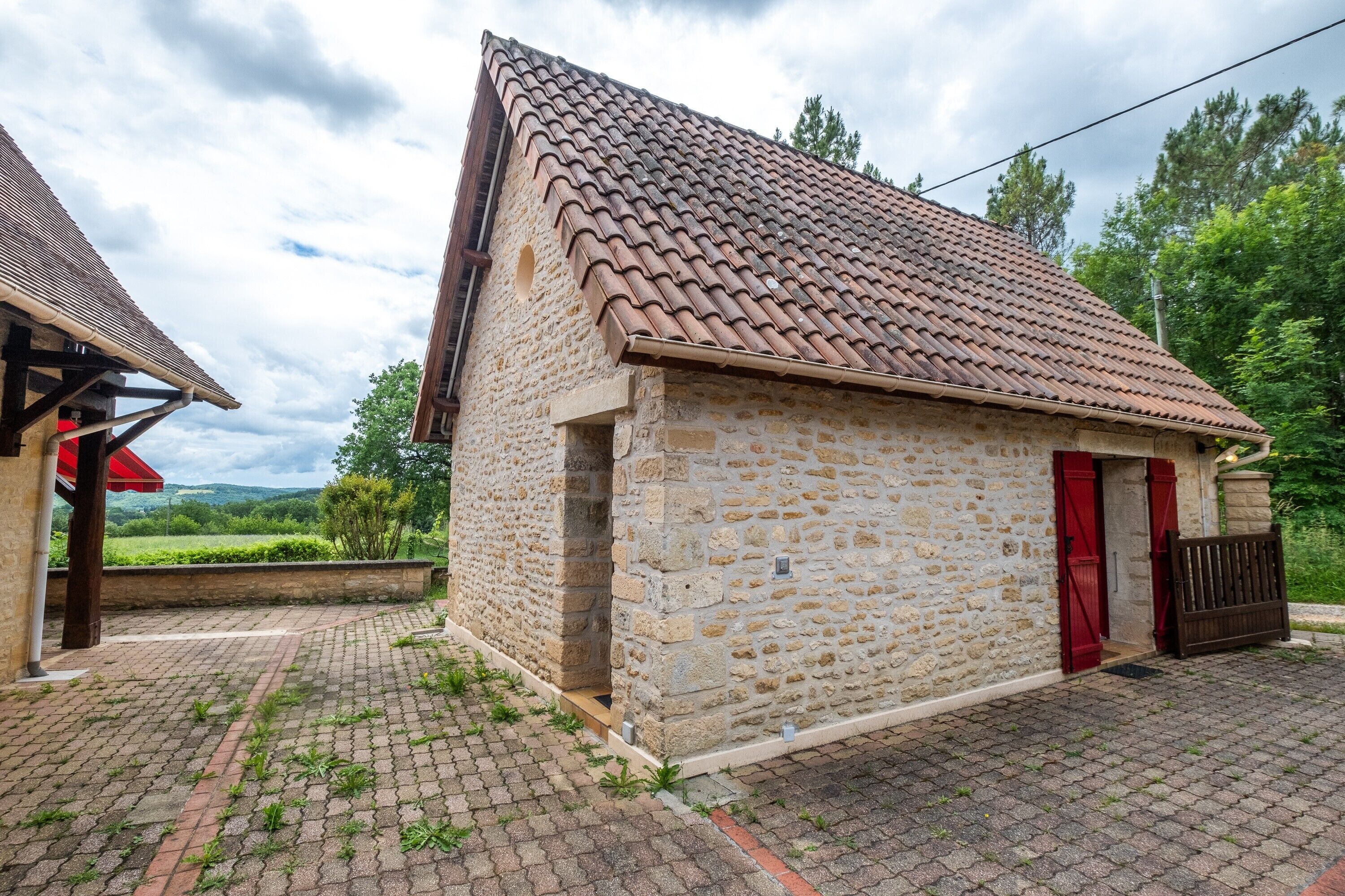 A stone building with a tiled roof, a red door, and a brick pathway.