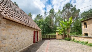 A stone building with a tiled roof, a paved courtyard, and a gated entrance. - Holiday Home “Panissal – Family 4 Guests” with Private Terrace (MONTIGNAC)