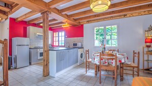 A kitchen with a central island, a dining area with a table and chairs, and a window with a view of greenery. - Holiday Home “Panissal – Family 4 Guests” with Private Terrace (MONTIGNAC)