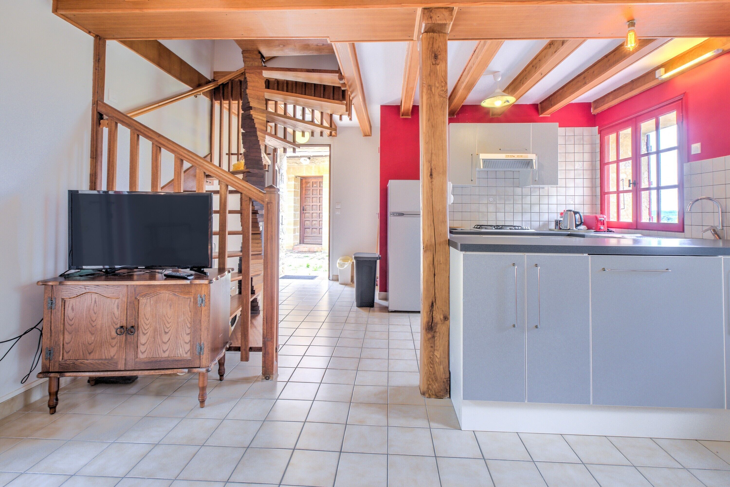 Une cuisine équipée d’une cuisinière intégrée, d’un réfrigérateur et d’un escalier en bois menant à un palier.