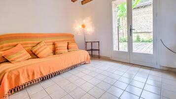 Quarto com cama, porta para o exterior e uma pequena mesa.