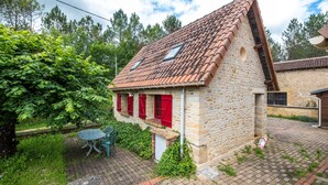 A stone house with a tiled roof, red shutters, and a small garden area with a table and chairs. - Holiday Home “Panissal – Family 4 Guests” with Private Terrace (MONTIGNAC)