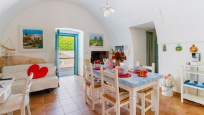 A dining area with a table set for four, a sofa with a heart-shaped pillow, and a painting of a landscape.