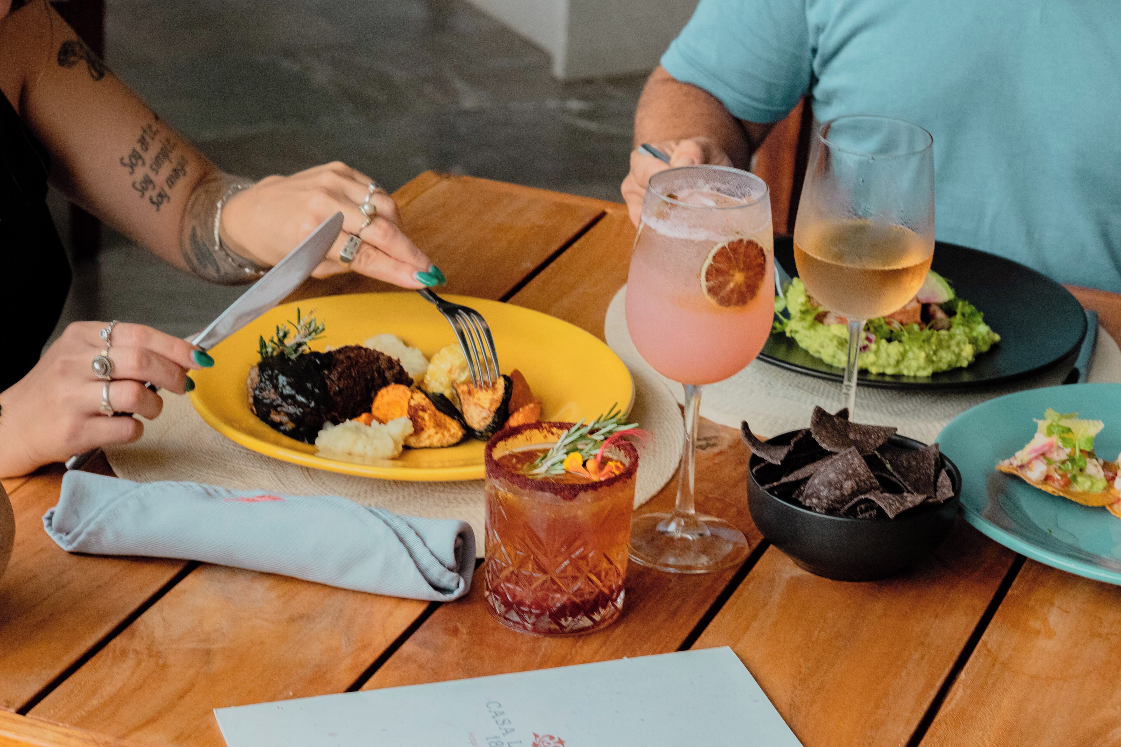 Una mesa con un plato de comida, una bebida y una servilleta.