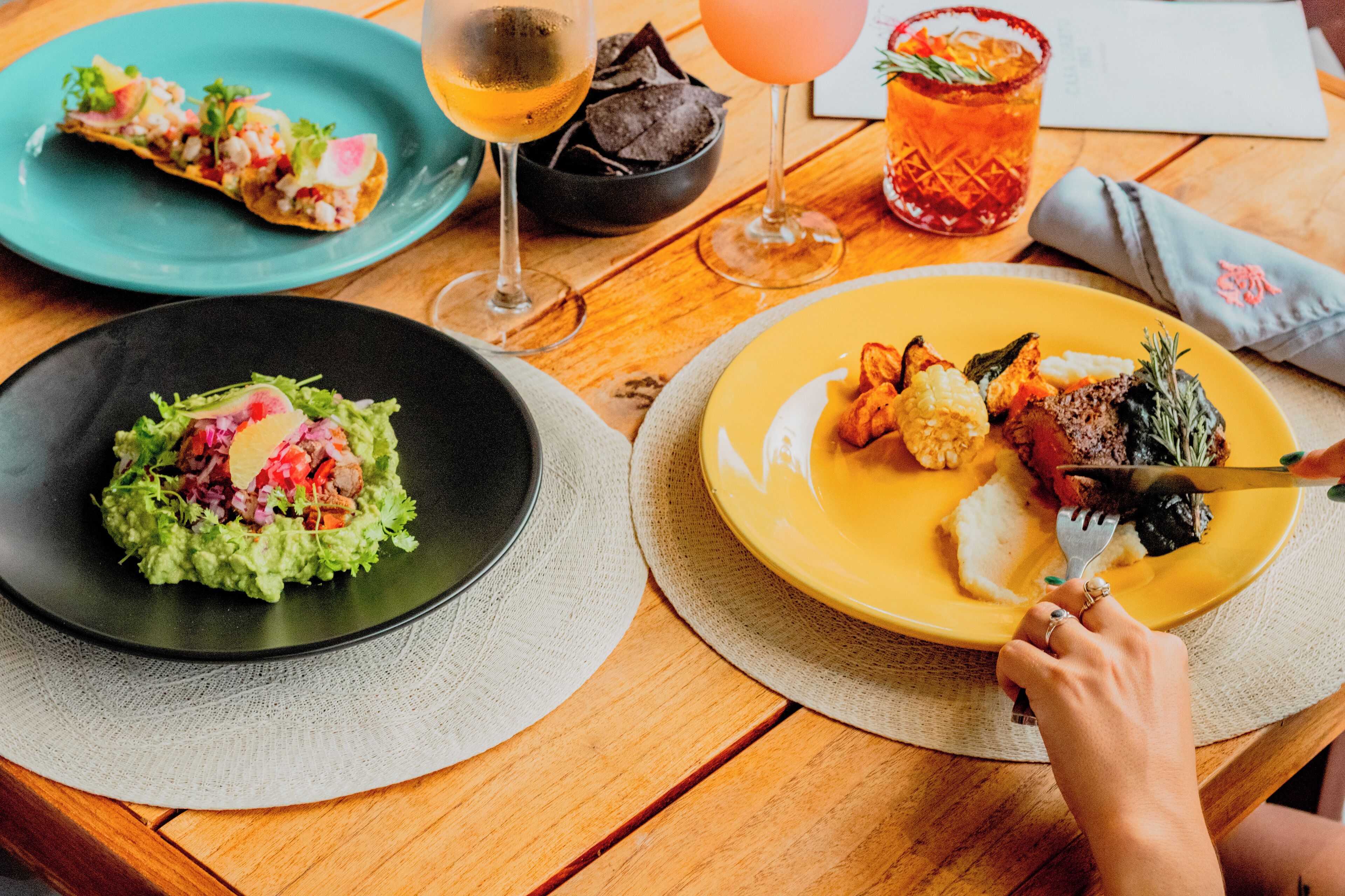 A table with two plates of food, two glasses of drinks, and a napkin.
