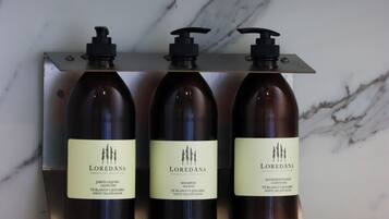Tres botellas de champú Loredana sobre un estante de mármol.
