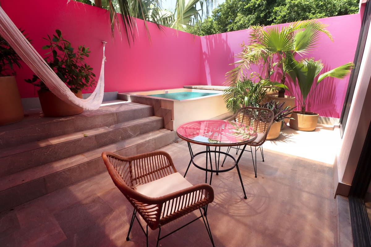 Un patio con hamaca, piscina y plantas en macetas.