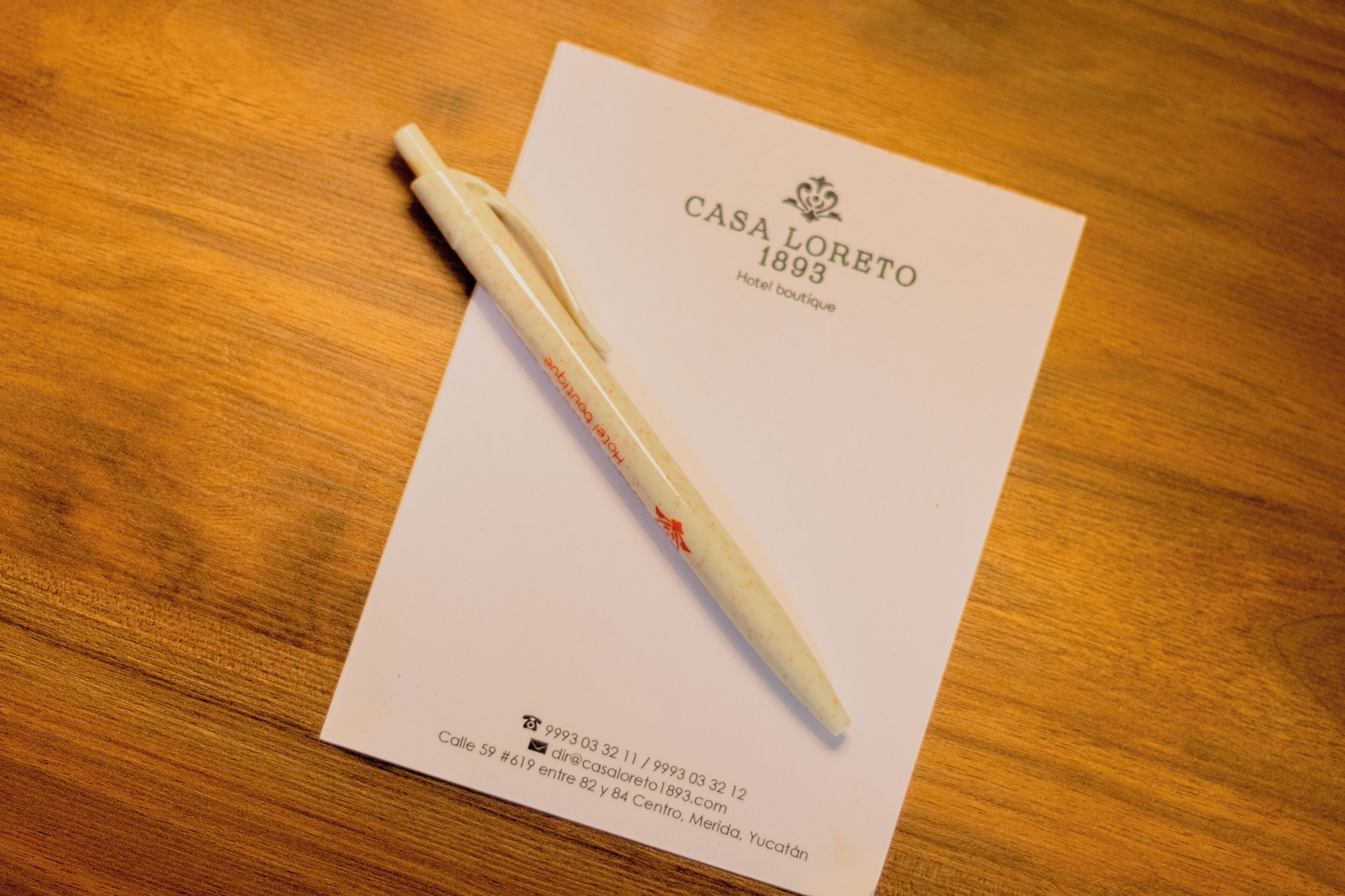 A business card for Casa Loreto 1893, Hotel boutique, with contact details and address.