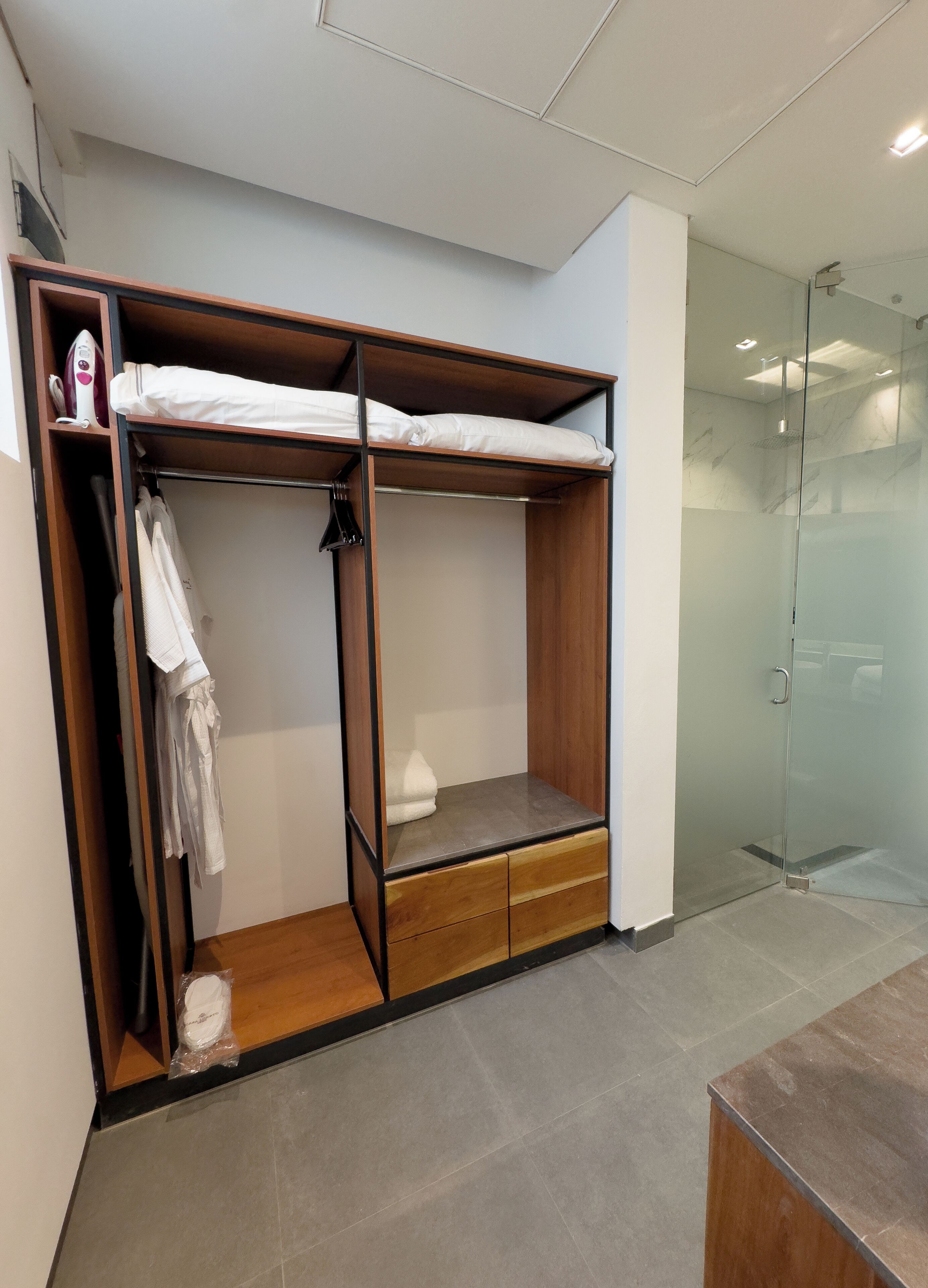 Habitación compacta con literas de madera, una pequeña zona de estar y cabina de ducha de vidrio.