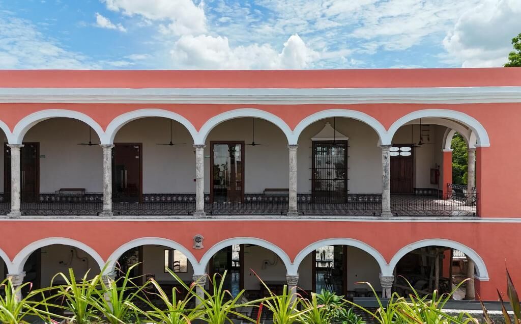 Un edificio con fachada roja y arcos blancos, que cuenta con varios balcones y un espacio abierto central.