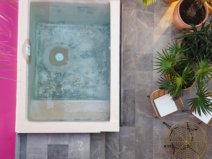 Un área de spa con jacuzzi, plantas en macetas y una silla de mimbre.