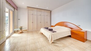 A bedroom with a bed, bedside table, wardrobe, and a small table with a vase. - Villa 'Costacabana -  Marysol' with Sea View, Private Pool and Wi-Fi (Lloret de Mar)