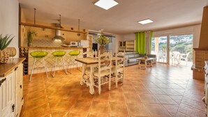 A spacious kitchen with a dining area, a living room with a sofa and a view, and a balcony with outdoor seating. - Villa 'Costacabana -  Marysol' with Sea View, Private Pool and Wi-Fi (Lloret de Mar)