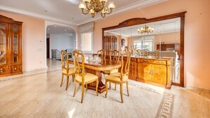 A spacious dining area with a large wooden table and chairs, a chandelier, and a mirrored cabinet. - Villa 'Costacabana -  Marysol' with Sea View, Private Pool and Wi-Fi (Lloret de Mar)