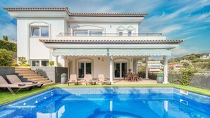 A two-story house with a swimming pool, outdoor seating, and a covered patio.