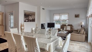 A dining area with a table set for four, a sofa, and a television in the background.