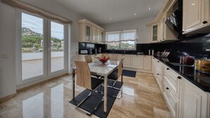 A modern kitchen with a dining area, large windows, and a view of the outdoors.