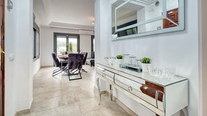Una cocina moderna con encimera de vidrio, armarios blancos y un espejo grande.