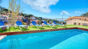 A swimming pool with blue water, surrounded by a wooden deck and a metal fence.
