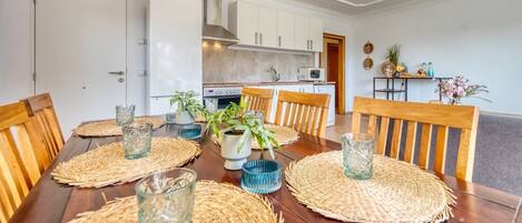 A dining area with a wooden table, woven placemats, and glassware.