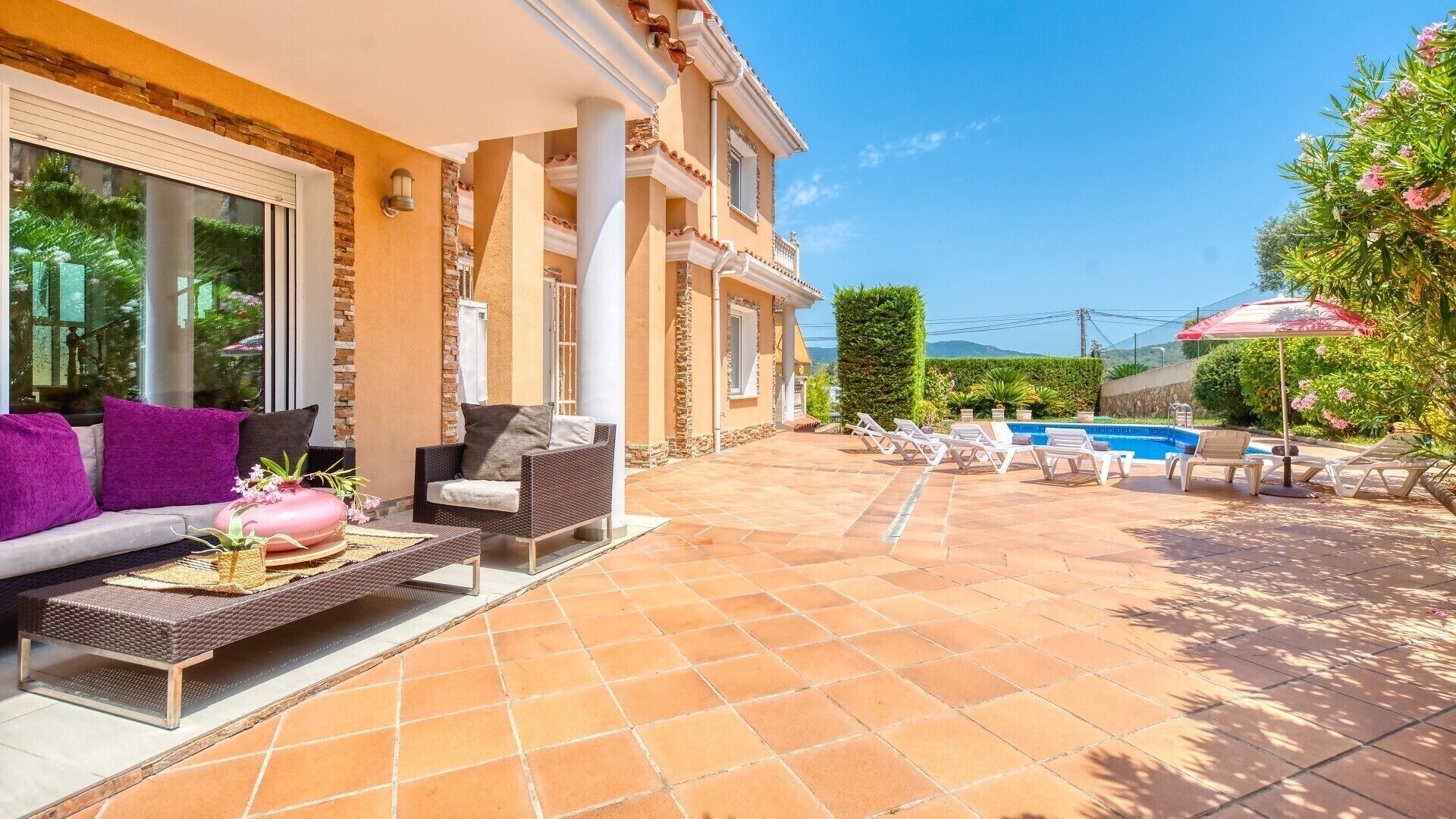 A patio with outdoor furniture, a swimming pool, and a view of the mountains.