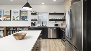 A modern kitchen with a large island, stainless steel appliances, and a dining area with chairs.