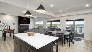 A spacious living area with a large island, a fireplace, and a view of the outdoors.
