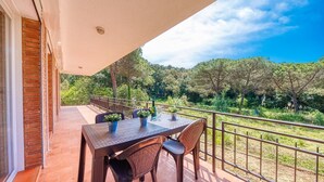 A balcony with a table and chairs, overlooking a lush green landscape.