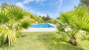 A swimming pool surrounded by grass and palm trees. - Villa "Costacabana - Lloret" with Shared Pool, Private Terrace & Wi-Fi (Lloret de Mar)
