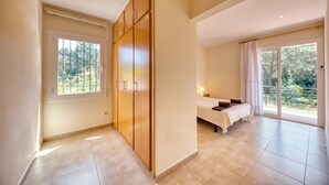 A bedroom with a bed, a wardrobe, a window, and a balcony.
