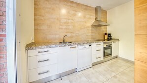 A kitchen with white cabinets, a granite countertop, a stainless steel sink, a range hood, and a coffee maker.